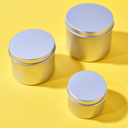 Set of three silver aluminum tins with lids against a yellow background